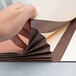 A hand cutting a brown and white Pendaflex file pocket.