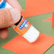 A hand using an Elmer's Clear glue stick to glue a piece of paper.