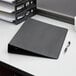 A Cardinal black legal size binder with a black cover sits on a table.