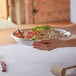 A person holding a Choice aluminum tray filled with food.