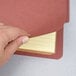 A person's hand using a Pendaflex letter size classification folder to write on yellow lined paper.