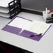 A purple Oxford 2-pocket file folder on a stack of papers on a desk.