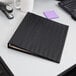 A black Cardinal horizontal easel binder on a desk.