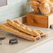 A silver wire pastry basket filled with bread on a counter.