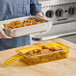 A woman holding a Cambro H-Pan with fried chicken.