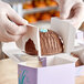 Hands holding a chocolate covered dessert in an Easter egg box.