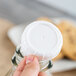 A hand holding a Libbey unlined white plastic lid on a glass bottle.