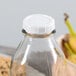 A Libbey glass milk bottle with a white cap.