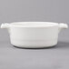 A white porcelain oval cocotte with handles.