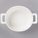 A white porcelain oval cocotte with two white handles.