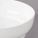 A close-up of a white Bon Chef curved bowl with a rim.