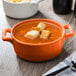 An orange porcelain oval bowl filled with food.