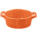 An orange porcelain oval cocotte with handles on a white background.
