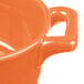 An orange porcelain oval cocotte with handles and a white interior.