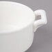 A close up of a white Bon Chef porcelain cocotte with a handle.