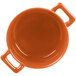 A white porcelain Bon Chef cocotte with handles and an orange interior.