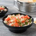 A black Thunder Group melamine salsa dish filled with salsa on a table.