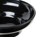 A close up of a black Thunder Group melamine salsa dish.