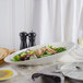 A salad in a white Bon Chef slanted oval bowl on a table.