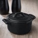 A matte black Bon Chef cocotte with a lid on a counter.