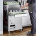 A man in a grey suit standing next to a Noble Warewashing under counter glass washer with glasses in it.