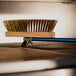 A close-up of a brass bristle brush on a metal surface.