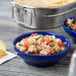 A blue bowl of salsa next to a bowl of chips.