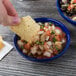 A person holding a chip in a Thunder Group cobalt blue melamine salsa bowl.