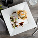 A Bon Chef square bone china plate with food on it on a table.