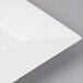 A close-up of a Bon Chef white bone china square plate with a white rim.