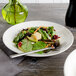 A white Bon Chef porcelain salad plate with a salad on it.