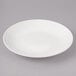 A white Bon Chef porcelain salad plate with a rim on a gray surface.