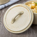 A Bon Chef wheat porcelain lid with a handle on a bowl of macaroni and cheese.