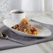 A white porcelain bowl filled with dessert with a cup of coffee on the table.