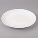 A white Bon Chef porcelain dinner plate with a white circle on the rim on a gray surface.