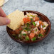 A hand holding a chip over a bowl of chocolate salsa.