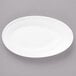 A white Bon Chef porcelain oval plate with a curved edge on a gray surface.