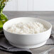 A white Bon Chef porcelain bowl filled with rice on a table.