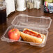 A hot dog with ketchup and an apple in a Durable Packaging clear plastic container with a hinged lid.