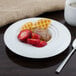 A plate of waffles with strawberries and a Bon Chef white porcelain bowl on a table.
