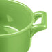 A close-up of a green Bon Chef porcelain cocotte with handles.