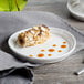 A white Bon Chef porcelain plate with food on it on a table.