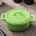 A lime green Bon Chef oval cocotte lid on a table.