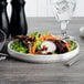 A white porcelain plate with a salad of carrots and lettuce.