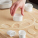 A person using Ateco oval pastry cutters to cut dough on a wooden surface.