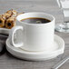 A white porcelain saucer with a cup of coffee and a plate of pastries.