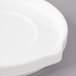 A close-up of a white Bon Chef Stacked Lines porcelain saucer.