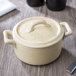 A white Bon Chef porcelain cocotte with a handle.
