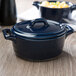 A cobalt blue Bon Chef porcelain oval cocotte with a lid on a table.