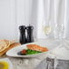 A plate of food with a piece of meat on top of peas served in a Bon Chef white porcelain bowl on a table.